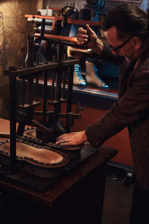 Experienced man is using a press tool at his new workshop.