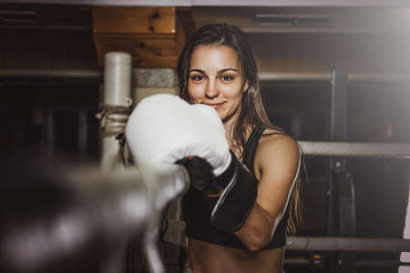 Happy smiling female boxer is ready to fight while standing at her corner on the ring.の写真素材