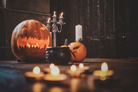Halloween traditional carved pumpkins, small boiler and candles on the wooden floor.の写真素材