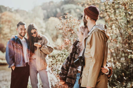 In the bright sunny day group of friends are enjoying their walk at autumn forest.の写真素材