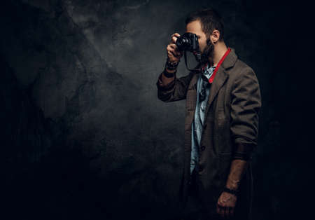 Focused young photographer is taking a photo on the dark grunge background.の写真素材