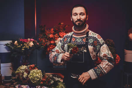 Experienced bearded florist is creating nice bouquet using variety of flowers.の写真素材