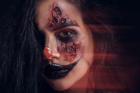 Photo of creepy Halloween evil clown with red light and big exposition, creating movement effect.の写真素材