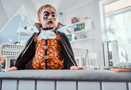 Portrait of little gloomy boy in Halloween costume vampire at festive party.の写真素材