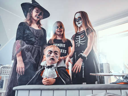 Funny smiling teens and gloomy little boy in Halloween costumes are enjoying their party.の写真素材