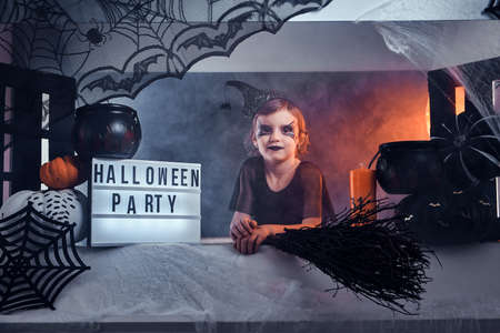 Little witch invite her friends for a party, she is sitting in well decorated area, there are spider...