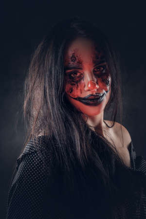 Portrait of evil Halloween clown with red light on the face at dark photo studio.の写真素材