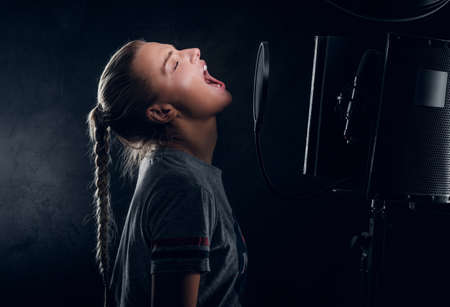 Charming cool student is singing her new song at recording studio.の写真素材