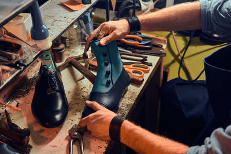 Experienced shoemaker is creating retro leather shoes at his comfortable workshop.の写真素材