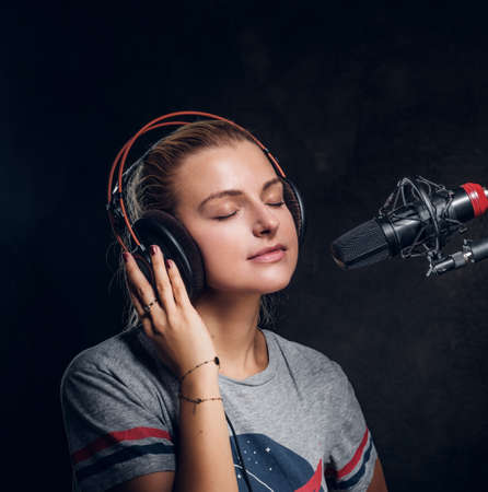 Recording a new song - attractive singer is singing new audio material.