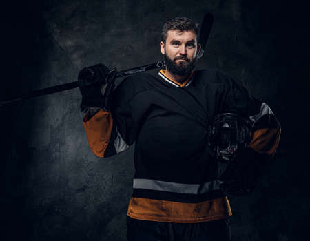 Portrait of brutal bearded man in hockey player uniform at dark photo studio.の写真素材