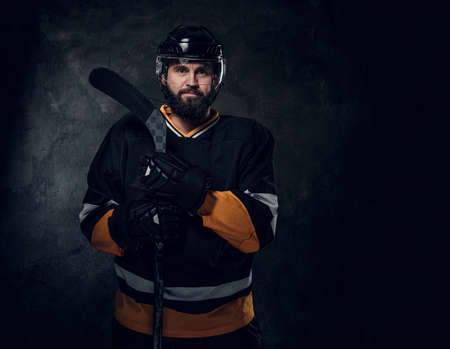 Professional bearded man in hockey player gear is posing for photographer.の写真素材