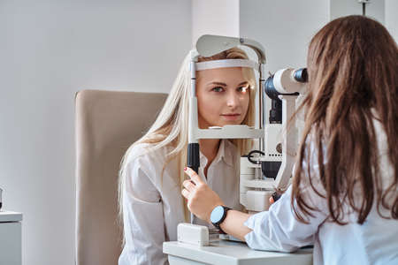Attractive woman is doing eye test in optical clinic with experienced oculist.の写真素材