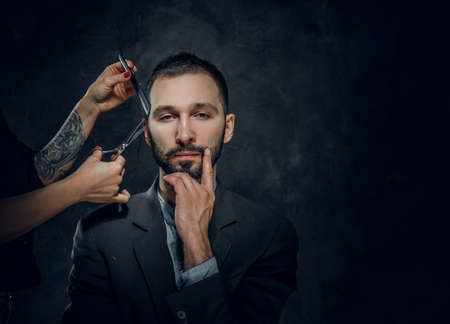 Confident elegant businessman receive a beard care from female with nice manicure.の写真素材