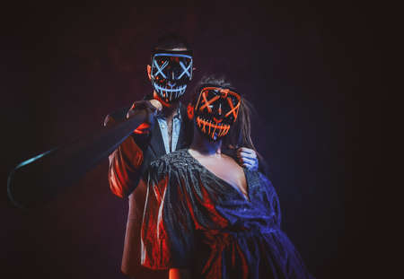 Crazy couple in spooky masks are posing for photographer with baseball bat.の写真素材