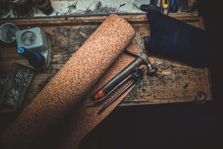 Workplace bench of cobbler with different tools on it and peace of textured fabric.の写真素材