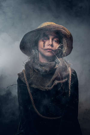 Evil creepy scarecrow concept - young woman in mist and smoke is posing for photographer.の写真素材