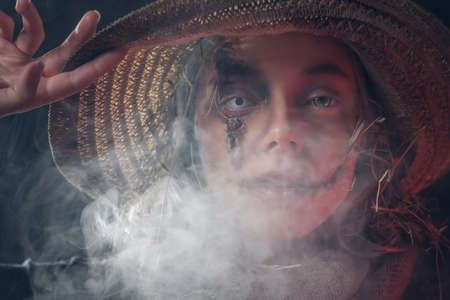 Beautiful woman in straw hat and with creepy eye lens is posing for photographer in smoke.