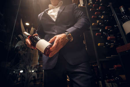 Expirienced wine sommelier is choosing good wine for tasting at private wine cellar.の写真素材