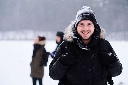 Happy young hiker posing in a camera stand next to her friends in the snowy forestの写真素材