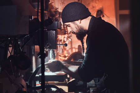 Experienced leather master is working on his new project at the dark workshop.の写真素材