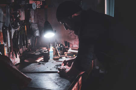 In the busy workshop talented master is making his masterpeace from leather.