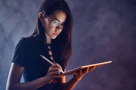 In a dark room beautiful young gfirl is making a creative sketces for he new puppet show.