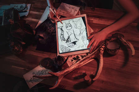 Talented girl is sketching on a digital tablet while sitting on her cozy studio.の写真素材