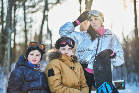 Young mother with two sons are posing for photographer at sunny winter forest.の写真素材