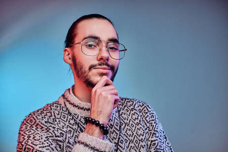 Young attractive man in glasses is posing for photographer at studio.の写真素材