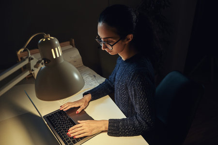 Pretty woman in glasses is working using a laptop at her office.