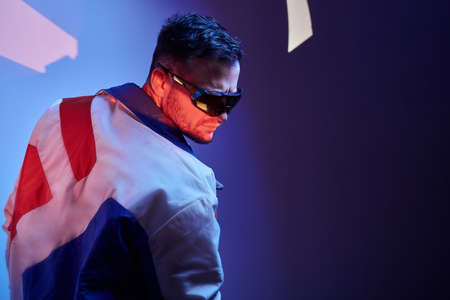 Handsome man in sunglasses is demonstrating his cool jacket at photo studio.の写真素材