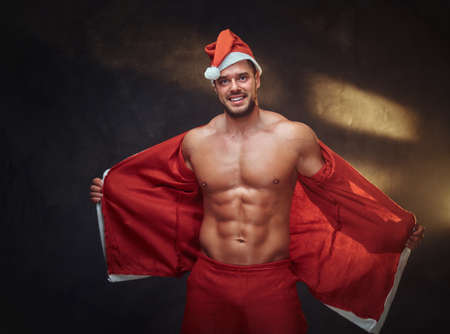 Sexy shirtless Santa in traditional red costume is posing at photo studio.の写真素材