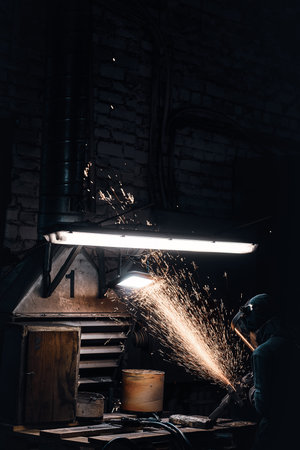 Sparks are flying away while worker in protective uniform is cutting metal.の写真素材