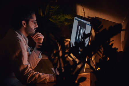 Handsome young doctor is working at late night shift at his office using a computer.の写真素材