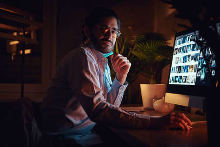 In the night shift pensive doctor in glasses is working with x-ray images using computer.の写真素材