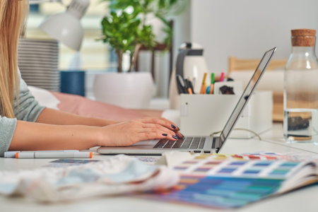 Woman with nice manicure is working on computer at creative studio.