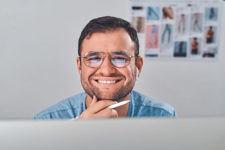 Cheerful smiling man in glasses and with pen in hand feels very happy.
