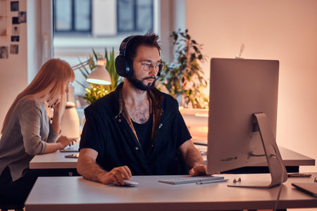 Two focused colleagues are working in the office using computers.