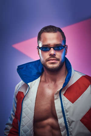 In the studio with neon background young handsome man in retro jacket has a photo session.の写真素材