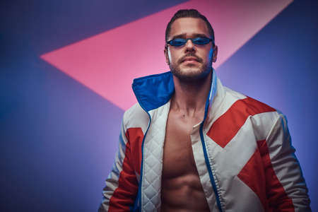 Young attractive man in sunglasses is posing for photographer on the neon background.の写真素材