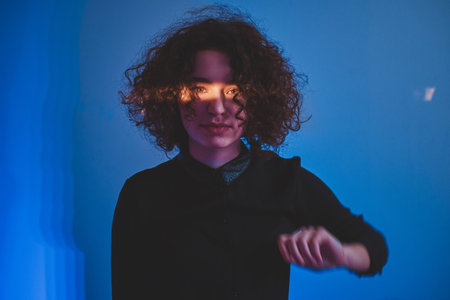 Beautiful sensual woman is posing for photogrpher with stripe of light on her face.