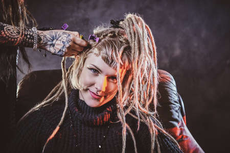 Young pensive woman got new freaky hairstyle from dreadlocks master.の写真素材