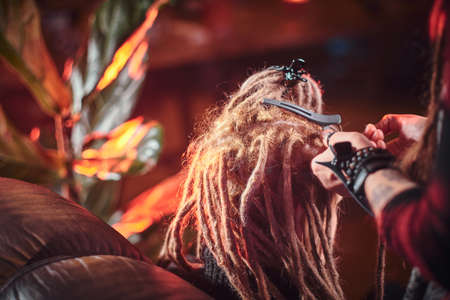 Process of dreadlocks making in the hair studio, blond girl receives a good service.の写真素材