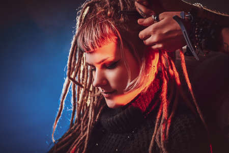 Pretty young woman is receiving new hairstyle from dreadlocks master.の写真素材