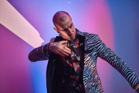 Hot, daring, tattooed, bald male model posing in a studio for the photoshoot wearing fashionable...