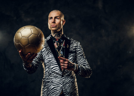 Elegant, vivid, tattooed, bald male model posing in a studio for the photoshoot wearing fashionable...