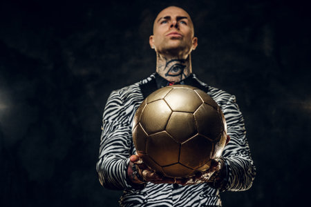 Bold, vivid, tattooed, bald male model posing in a studio for the photoshoot wearing fashionable...