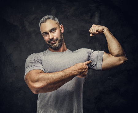 Handsome, adult, fit muscular caucasian man posing for a photoshoot in a dark studio under the...
