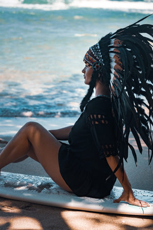 Beautiful and confident semi-nude female wearing american indian traditional headdress, while...